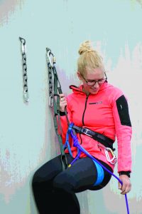STEP 1: When you arrive at the anchor, stay on belay and clip in with a PAS, or a sling or quickdraw. In our example we show the leader clipped to one anchor bolt— her lead rope is still clipped through the bolts below her, backing up the anchor, and she remains on belay.