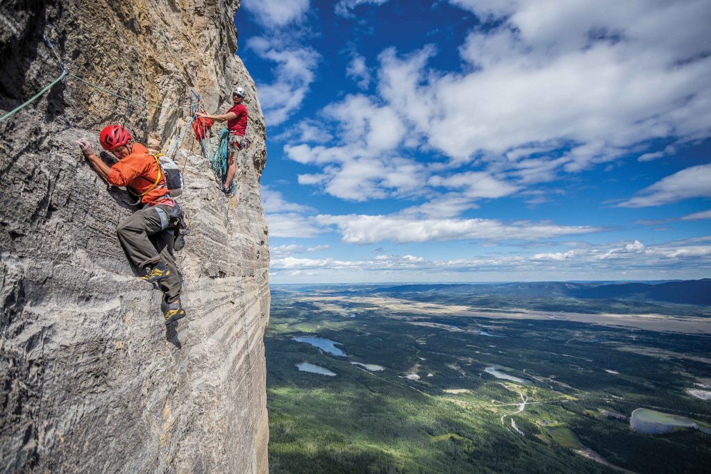 Patrick Lindsay holds the rope for Tim Banfield on one of many traverse pitches of Forbidden Corner (5.9), Mt. Yamnuska, Alberta, Canada. Photo: John Price.