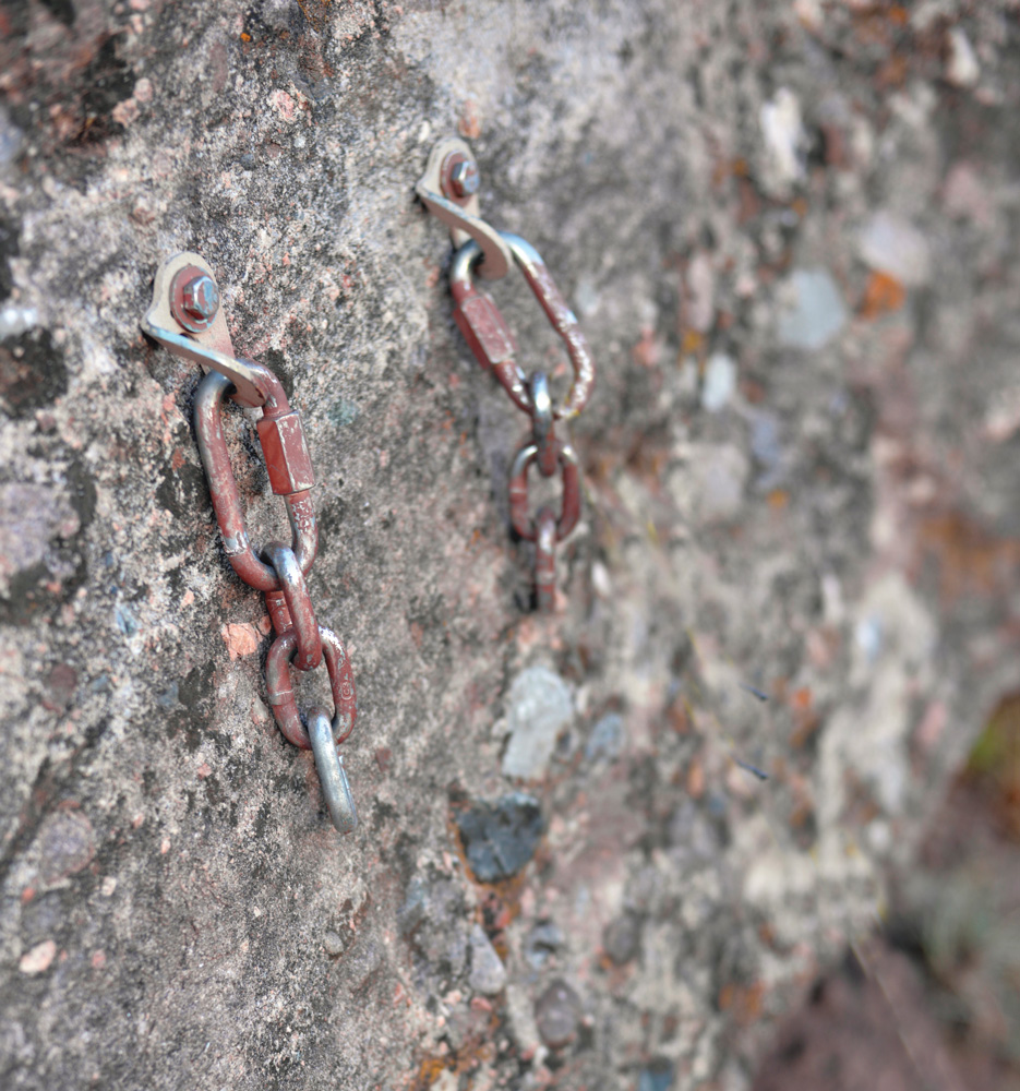 This anchor is only equipped with chains. In this situation, the leader will have to anchor, untie and thread the rope for a rappel. These chains and bolts have been camouflaged for minimal visual impact. Anchors on a rock climb.