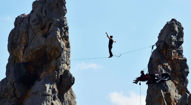 A slackliner walks the plank between Las Agujas (The Spires).
