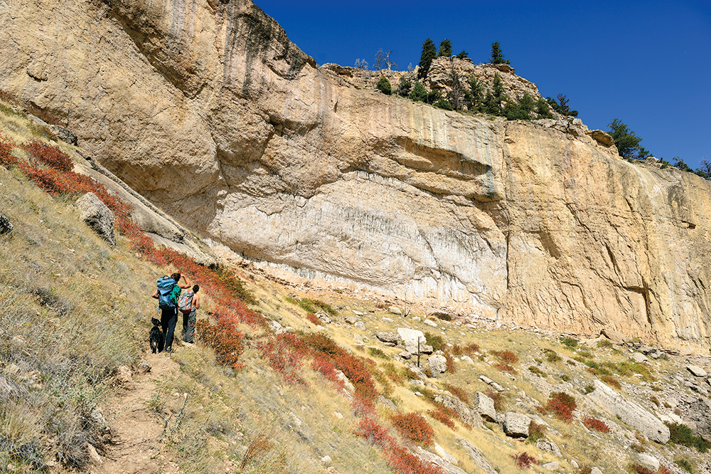 Siegrist and his dog Zeke, and B.J. Tilden standing below the cave at Wolf Point in northwestern Wyoming. Photo: Caroline Treadway.